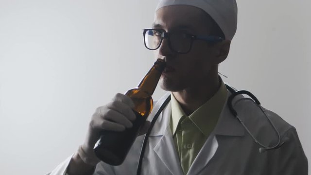 Portrait of Drunk doctor. A medical worker drinks beer.