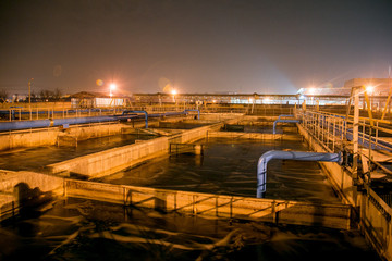 Modern wastewater treatment plant of chemical factory at night. Water purification tanks