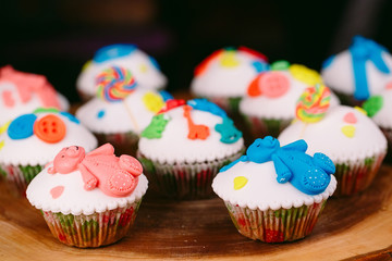 Baby cupcakes on the wooden background.