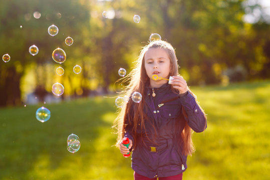 Girl play with soap bubbles.