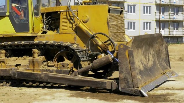 Yellow bulldozer in motion. Construction of a residential multi-apartment complex in the city. Construction. Stock video footage.