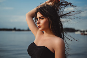 Naklejka premium Girl by the water holding hair in the wind