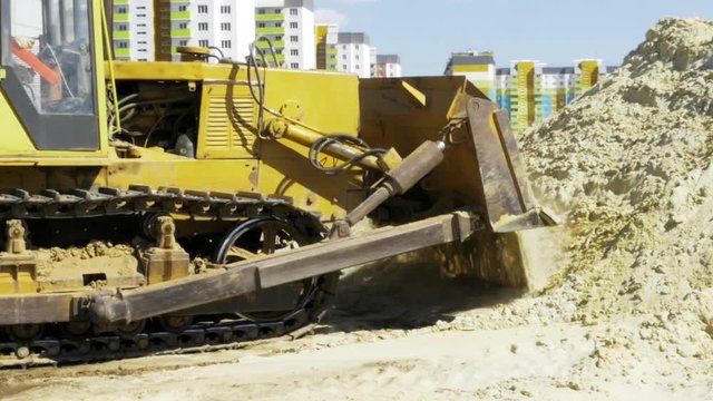 Yellow bulldozer in motion. Construction of a residential multi-apartment complex in the city. Construction. Stock video footage.