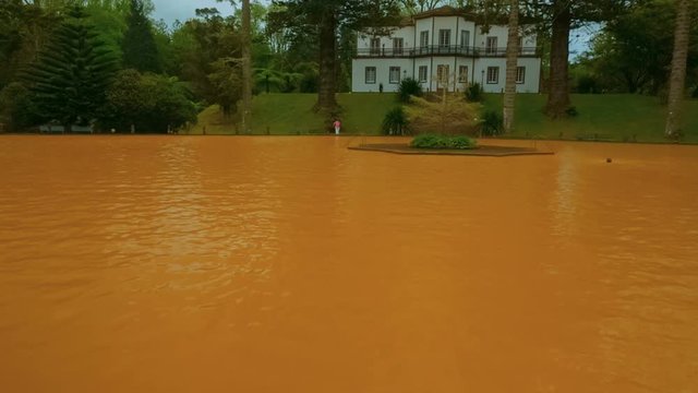 Tilting shot of yellow iron water heated thermal pool in the edenic Parque Terra Nostra, Furnas, Sao Miguel, The Azores, Portugal. 