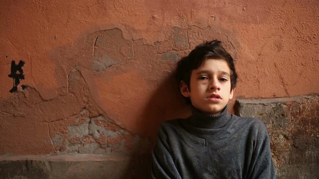 The boy is a teenager with a hematoma and a bruised eye that looks into the camera.