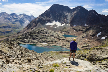 Hiking in Aosta valley, Italy. Hiker gazes at third lake of Lussert from Laures col.