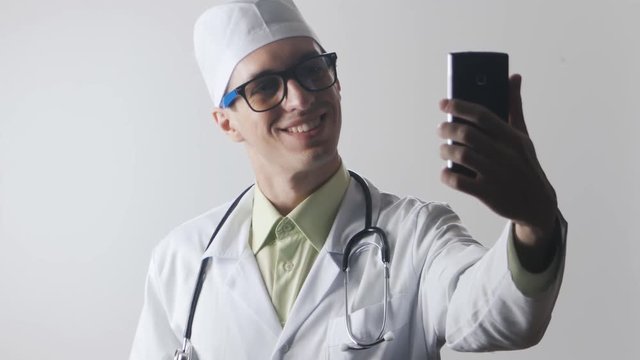 Doctor makes a selfie using a smartphone. The medical worker photographs himself.