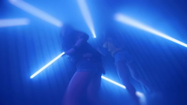 Sexy women dancing at night party. Close up of two girls energy dance. Women dancing at disco club. Dance party with neon lighting. Women shaking ass in slow motion at night club. Nightlife