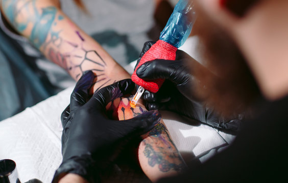 Professional tattoo artist makes a tattoo on a young girl's hand.