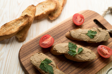 Liver pate on the bread on wooden tray.