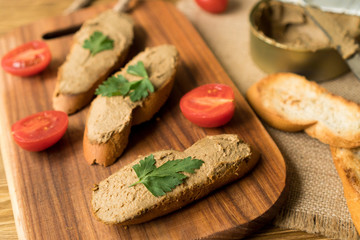 Liver pate on the bread on wooden tray.