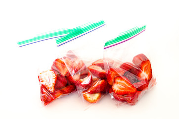 Studio shot fresh chopped strawberries in three clear plastic bag with lock isolated on white....