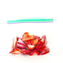 Studio shot of fresh chopped strawberries in clear sealed plastic bag with lock isolated on white. In-house cut, packed strawberry in transparent zipper bags to-go/take away. Convenience and healthy.