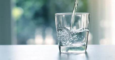 Fotobehang Water Sluit het gietende gezuiverde verse drinkwater uit de fles op tafel in de woonkamer