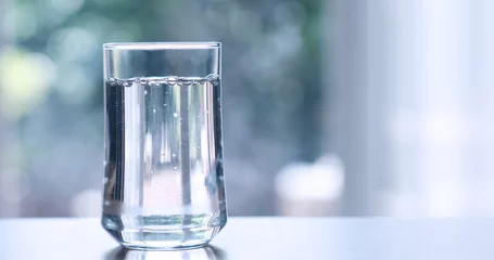 Foto op Plexiglas Close-up van gezuiverd vers drinkwater uit de fles op tafel in de woonkamer © Cozine