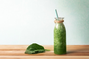 Healthy fresh  green smoothie juice in the glass bottle on wooden table for healthy detox and diet  habits concept