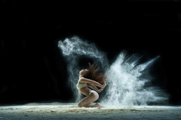 Fototapeta na wymiar Woman in a cloud of white dust studio portrait