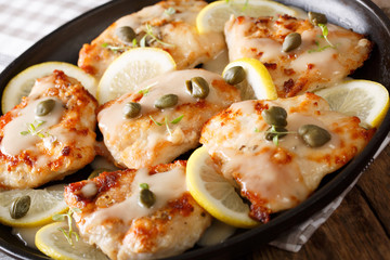 Italian chicken piccata with sauce, lemon and capers close-up. Horizontal