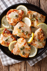 Italian food: chicken piccata with sauce, lemon and capers close-up. Vertical top view