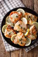 Italian chicken piccata with sauce, lemon and capers close-up on a plate. vertical top view