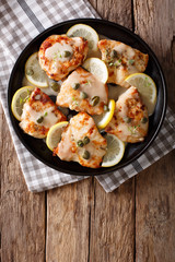 Italian cuisine: chicken piccata with sauce close-up on the table. Vertical top view