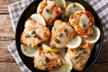 Italian food: chicken piccata with sauce, lemon and capers close-up. Horizontal top view