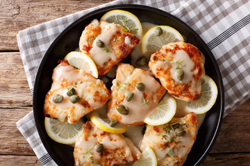 Italian chicken piccata with sauce, lemon and capers close-up on a plate. Horizontal top view