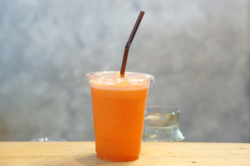 Closeup plastic glass of cold pressed juice on wooden table, Fresh mixed fruits, Healthy drink concept.