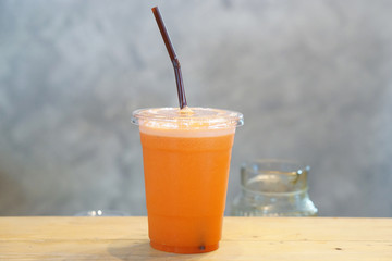 Closeup plastic glass of cold pressed juice on wooden table, Fresh mixed fruits, Healthy drink concept.