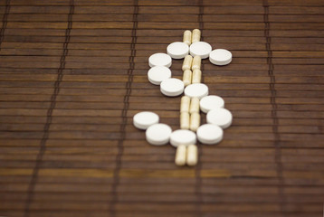 Emblem of dolor, lined with round tablets on a dark wooden background