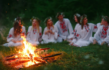 Midsummer night. Young people in Slavic clothes sitting near the bonfire.