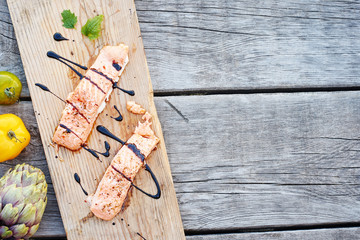 Top view of grilled salmon and fresh vegetables on a rustic wooden table. Healthy dinner with copy space. 