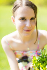 Portrait of a cute young woman with a bouquet of flowers in a summer park. Outdoor Portrait of a brunette girl with long hair in the nature