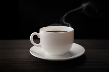 White coffee cup and coffee beans with smoke on black background