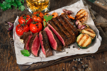 Sliced rare grilled steak with grilled vegetables and whiskey