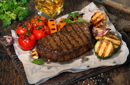 Beef grilled steak with grilled vegetables and glass of whiskey