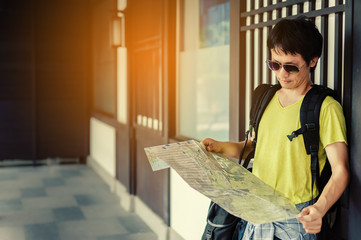 Asian Handsome man holding map with backpack.To prepare for travel,on Japanese-style buildings background,Image for travel and freedom life concept