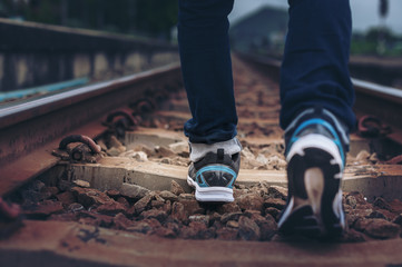 lifestyle image of man legs wear sport shoes walk on railway track 