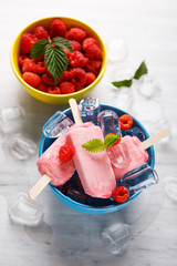 Raspberry ice cream popsicles in blue bowls.
