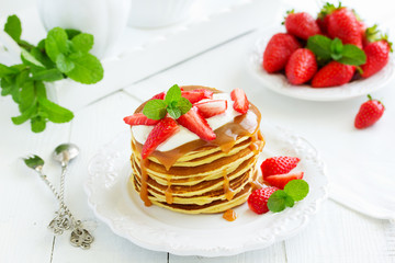 Pancakes with caramel and strawberries for breakfast.