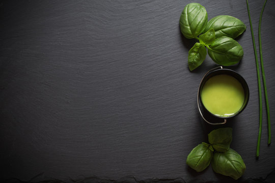 Basil and pesto sauce on a black background