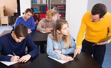 Male teacher clearing up complicated issue to pupil during exam in class