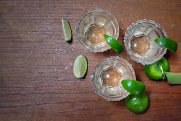 Tequila with lime and sea salt on wooden background top view.