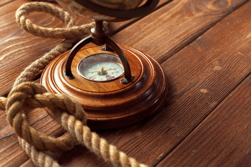 Compass and rope on wooden table. close up
