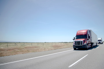 Semi trucks convoy on straight highway on flat plateau