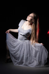 Fototapeta premium Actress in a grey dress on a dark stage