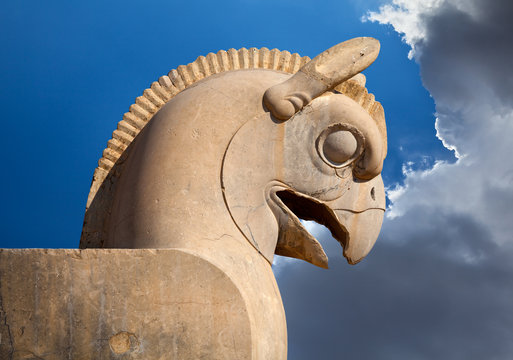 Statue of Huma or Homa Bird as decorative Column head in Persepolis against Blue Sky with White Clouds