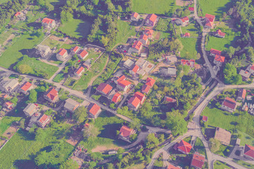 Top view of the village houses with red tiled roof on the green grass. Toned