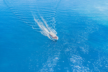 Top view of a pleasure boat with people floating on the blue sea