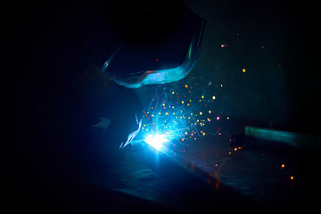 Professional welder in a factory welding steel bars